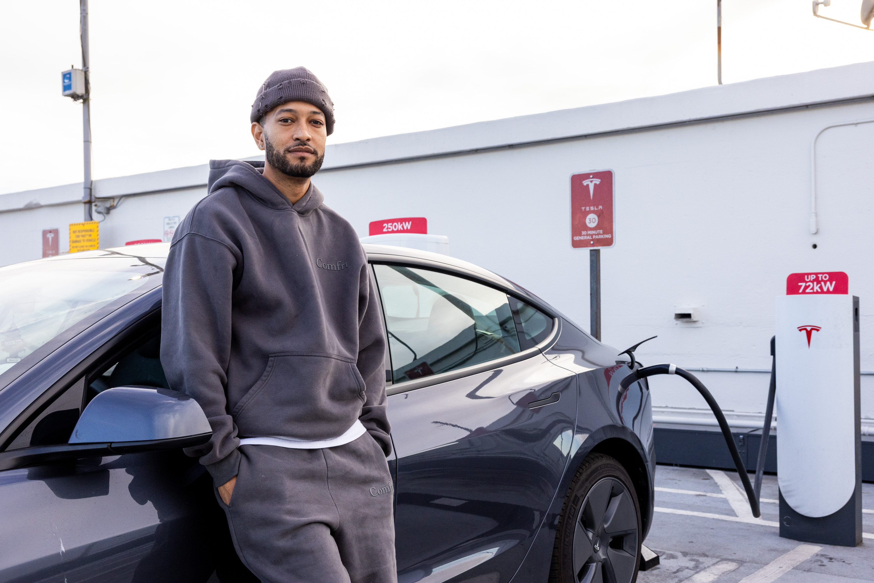 A man poses in front of his car